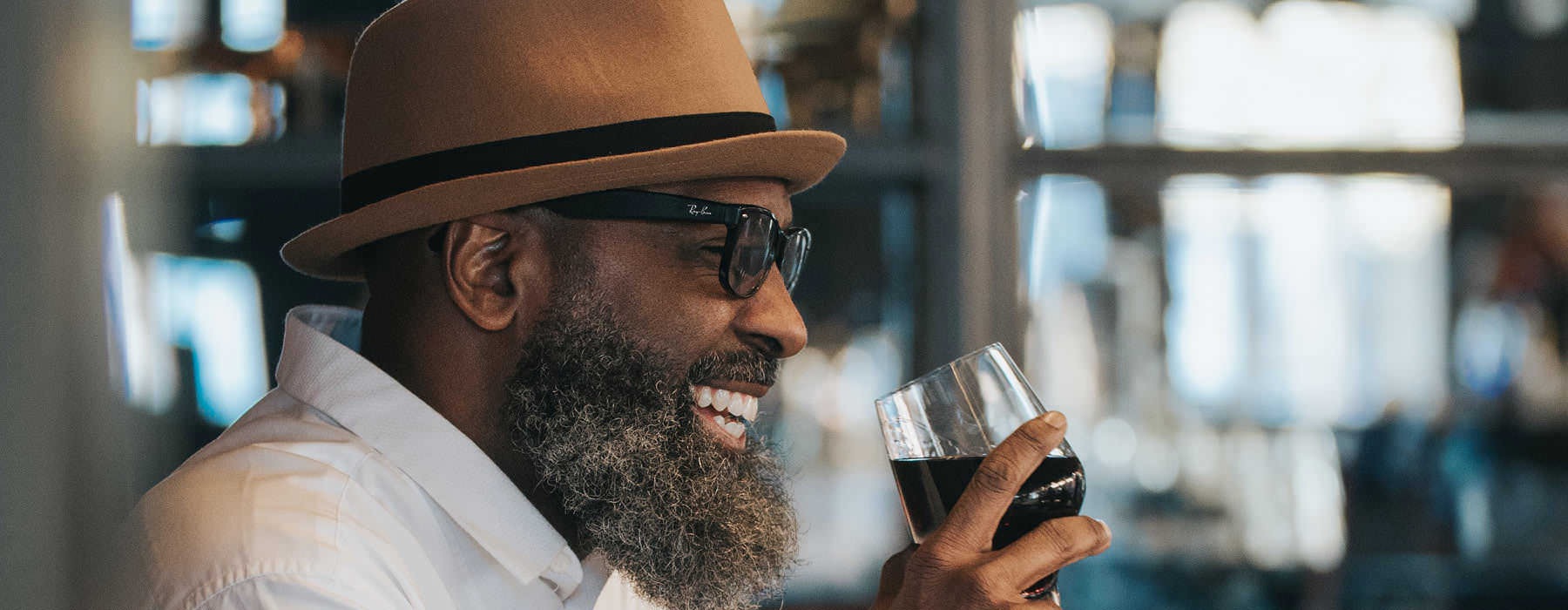 older man laughs with a glass of wine in local restaurant